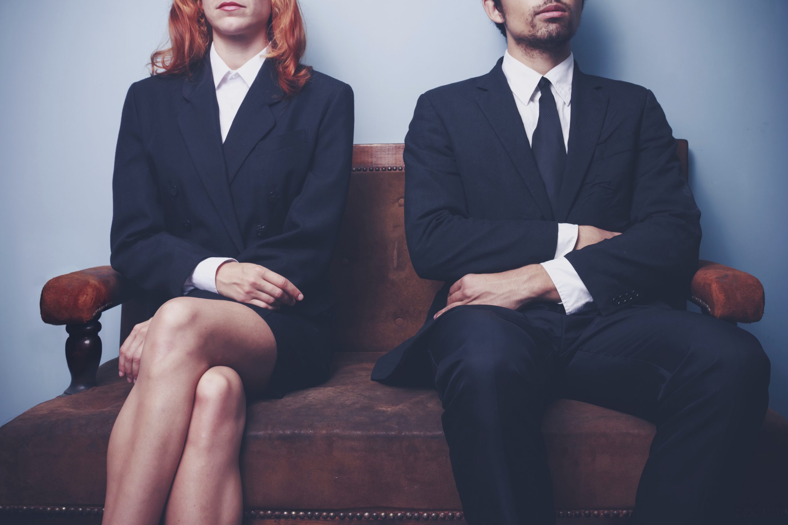 a man and woman sitting on the couch in professional clothing